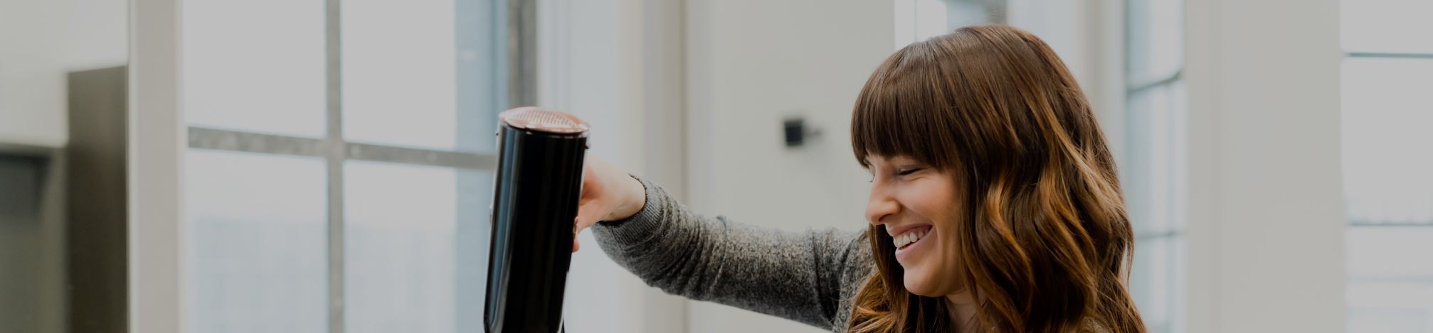 A hairdresser holding a hairdryer and smiling